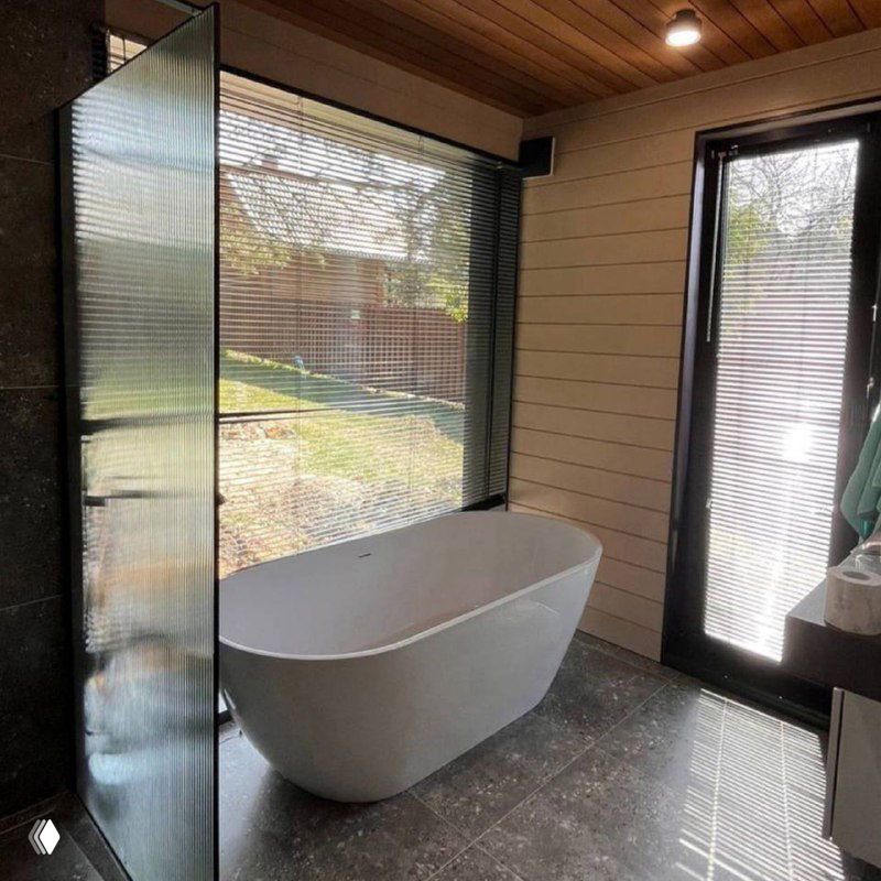 Ванная комната с окном и отдельно стоящей ванной — пример использования влагостойких стекол и оконных решений в санузлах.