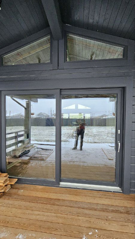 Монтажник стоит в проёме раздвижной двери GEALAN SMOOVIO; вид крупнее, демонстрирует пропорции створки относительно человека.