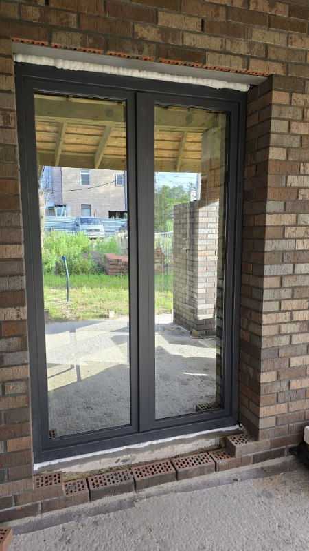 Готовое штульповое окно с антрацитовой ламинацией, выходящее на улицу, с аккуратной внешней отделкой и порогом.