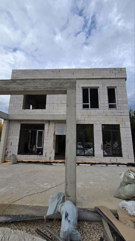Фасад дома на стадии черновой отделки с несколькими установленными окнами и проёмами — общий вид строящегося объекта и расположение окон.