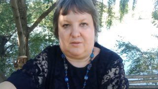 Портрет женщины среднего возраста на скамейке у реки среди зелени; участница, давшая эмоциональный отзыв о своём финансовом состоянии и участии в флешмобе.