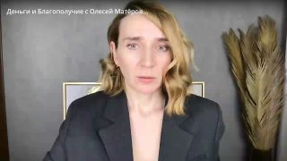 Женщина в тёмном пиджаке говорит в кадре на нейтральном фоне с декоративными травами — автор рассуждает о деньгах, страхах и сценариях благополучия.