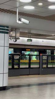 Платформа станции Шанхайского метро с автоматическими перегородками и поездом на станции, видны потолочные светильники и элементы системы безопасности.