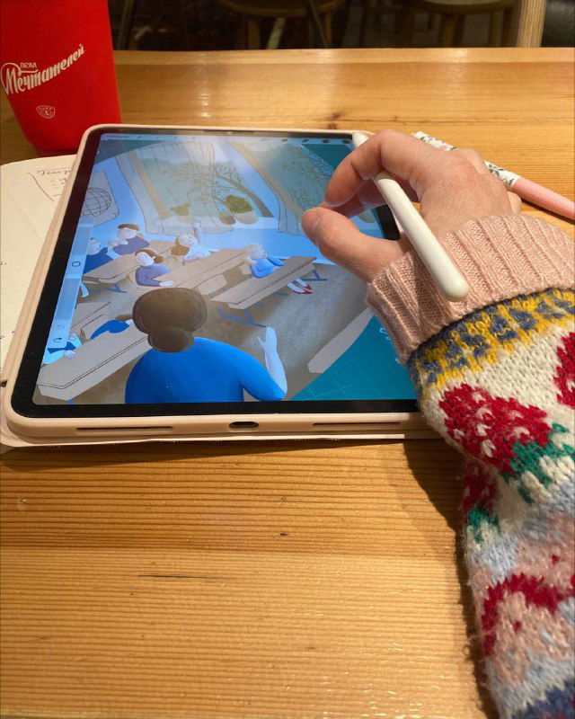 Рабочий кадр: планшет с цифровой иллюстрацией обложки и рука художника с стилусом, процесс доработки композиции и деталей класса на экране.