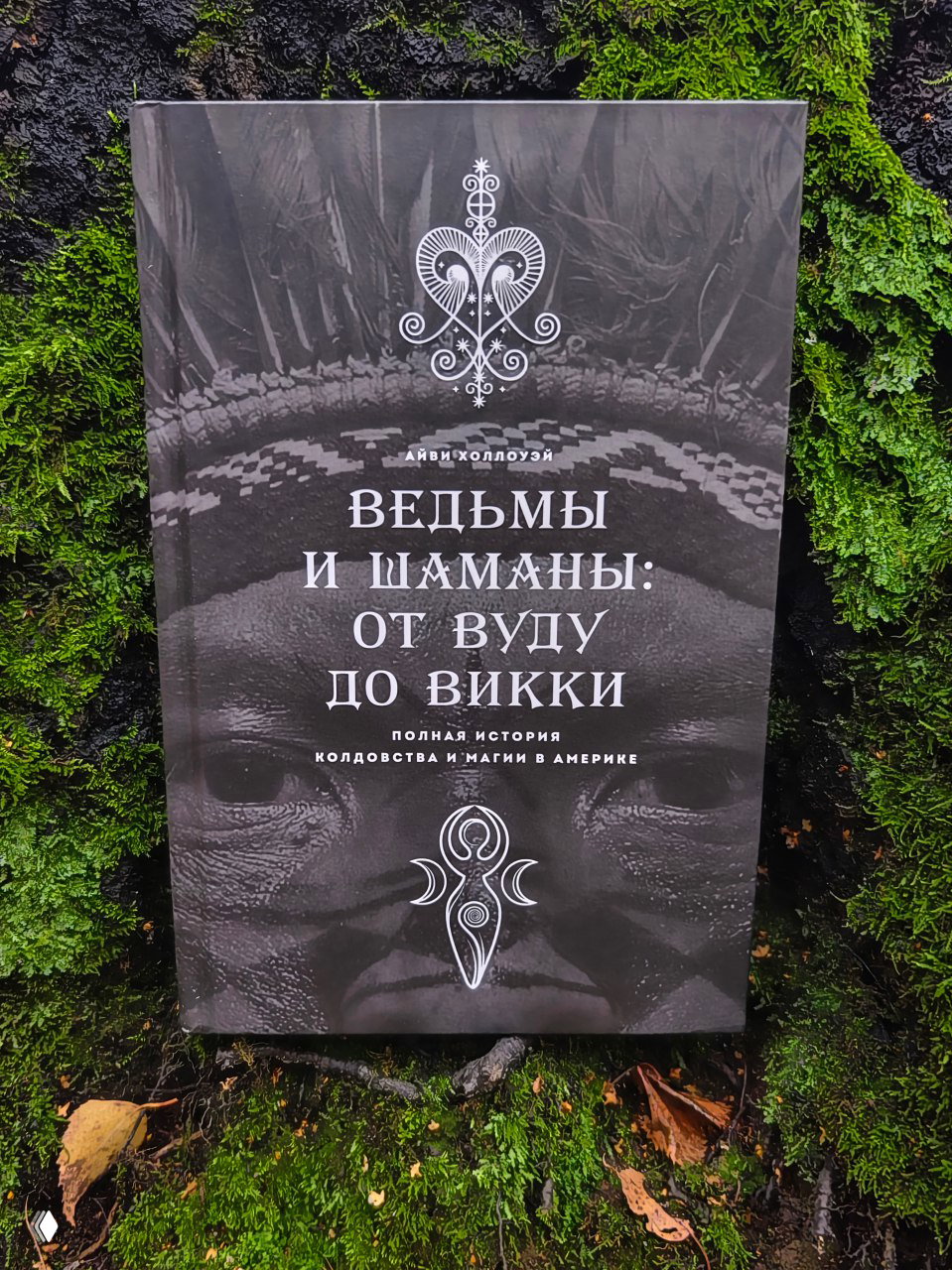 Чёрно-белая обложка книги «Ведьмы и шаманы: от вуду до викки» на мшистом фоне; декоративный орнамент и символика заметны на лицевой стороне.