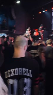 Поклонник в футболке с надписью DEXDBELL стоит в толпе перед сценой — снимок с концерта подчёркивает фанатскую поддержку и энергетику зала.