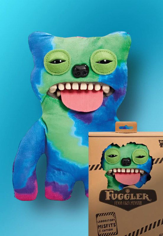 Плюшевый Fuggler голубо-зелёного цвета с языком и человеческими зубами на фоне бирюзового цвета, рядом коробка продукта