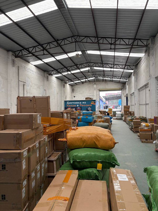Длинный коридор складского помещения Panda28 с разбросанными посылками и мешками, видна логистика внутри склада и процесс консолидации грузов.