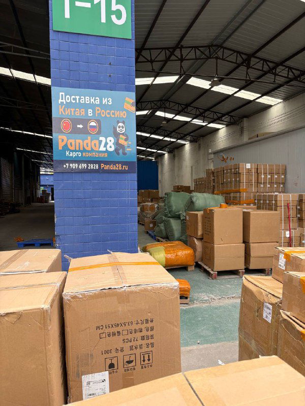 Паллеты и картонные коробки рядом с колонной и табличкой 1-15 на складе Panda28; вид зоны консолидации грузов и упаковки для отправки в Россию, фото для отчёта.