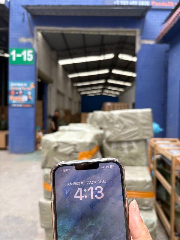 Рука держит смартфон на фоне склада Panda28 и упакованных пакетов; видна логистика и рабочая зона внутри двора.