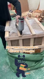 Рабочий в перчатках закрепляет деревянную транспортную коробку степлером на складе — подготовка отправки груза из Китая в Россию.