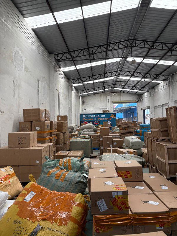 Складское помещение Panda28 с многочисленными посылками и упаковочными мешками на полу, подготовка грузов к консолидации и отправке.