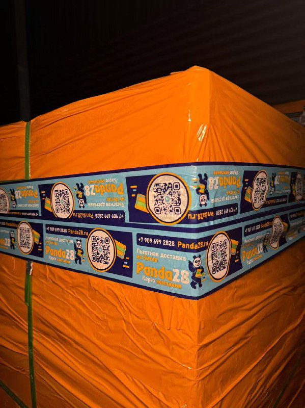 Ближайший план упакованного паллетного груза в оранжевой плёнке и брендированной ленте Panda28, готового к отправке международным перевозчиком.