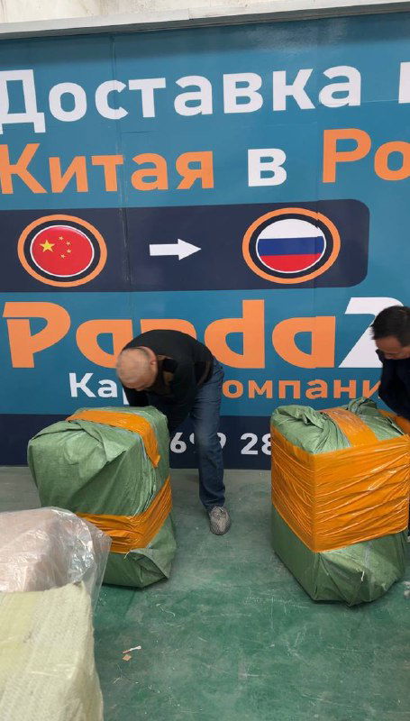 Упаковка и маркировка посылок у бренд-стенда Panda28: сотрудники обматывают грузы и готовят посылки к отгрузке на фоне фирменного баннера