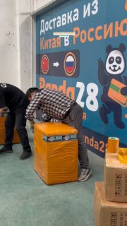 Сотрудники упаковывают и обматывают посылки на фоне баннера Panda28: процесс подготовки груза к отправке и крепления упаковки.