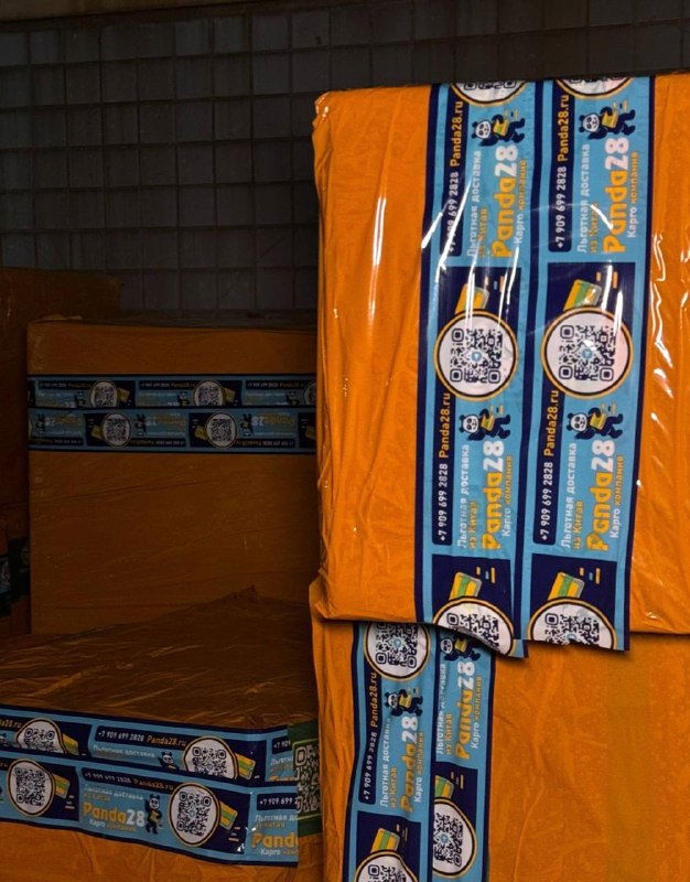 Упакованные коробки в оранжевой стрейч-плёнке с фирменной лентой Panda28 на складе, крупный план упаковки и маркировки для экспорта.
