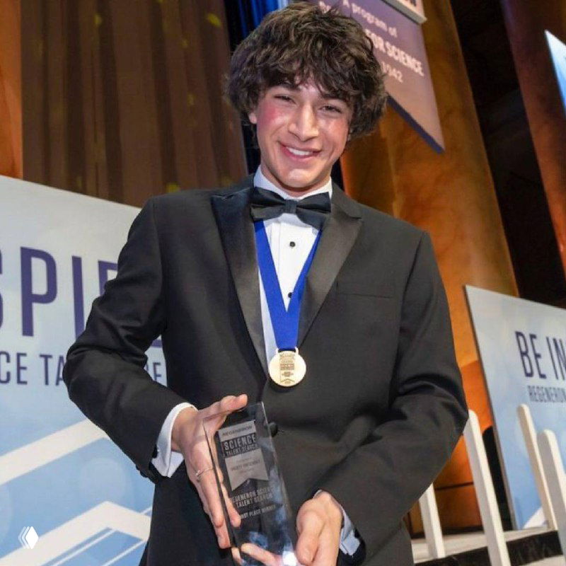 Молодой человек в смокинге с медалью и призом на церемонии награждения — торжественное фото, улыбается.