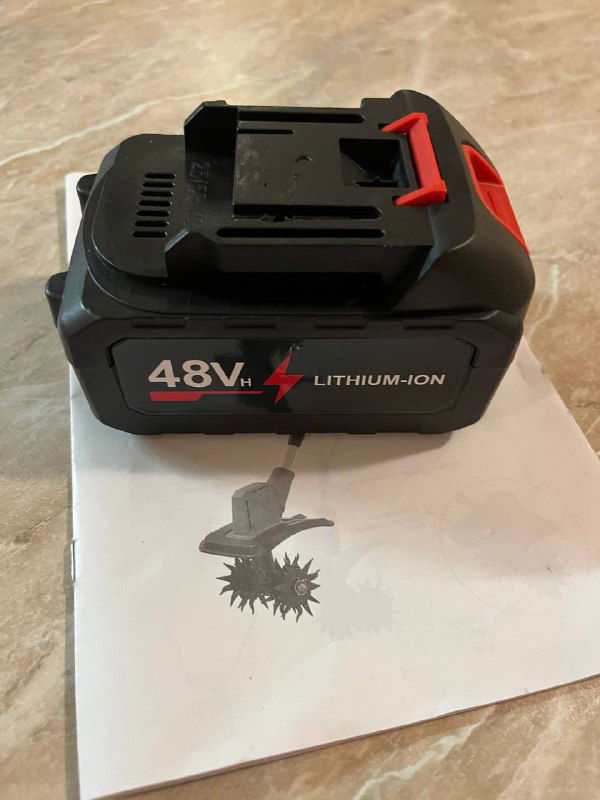 Крупный план литий-ионной аккумуляторной батареи с маркировкой «48V Lithium-ion», расположенной на инструкции к скарификатору; видна контактная зона и замок батареи.