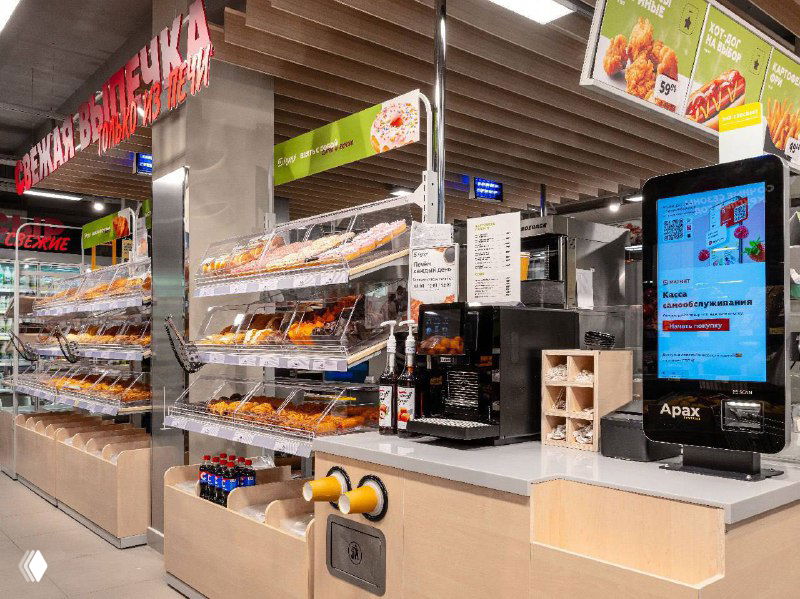 Кофе-станция и кассовая зона в формате «Заряд»: автоматы, кофемашина и цифровое меню на стойке рядом с витринами со снэками и выпечкой.