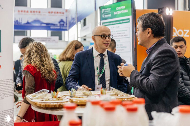 Деловое общение за демонстрационным столом: представители брендов обсуждают продукты и дегустационные образцы на выставке.