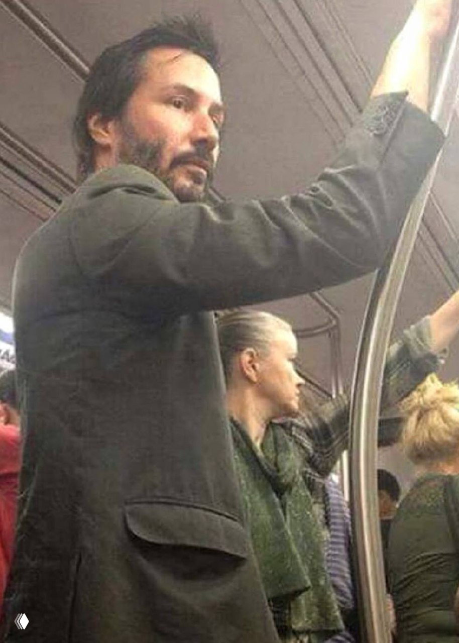 Снимок в городском метро: мужчина стоит в вагоне, держась за поручень, повседневный кадр из обычной городской жизни без помпы и позирования.