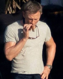 Человек на открытом воздухе держит сигару у лица, задумчиво смотрит вниз, видна напряжённая поза и момент перед затяжкой.