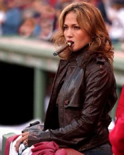 Женщина в спортивной обстановке держит сигару, кадр показывает, что ритуал курения выходит за рамки полов и символов статуса.