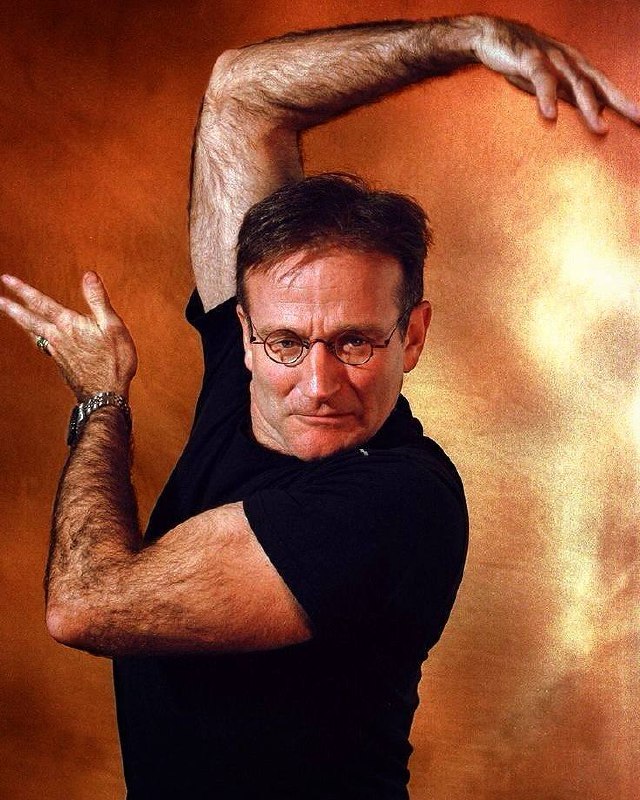 Динамичный портрет мужчины в выразительной позе на тёплом фоне; кадр подчёркивает экспрессию и движение образа.