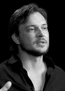 Черно‑белый портретный кадр мужчины, легкая небритость, сосредоточенное лицо — сценка из выпуска о спокойной уверенности.