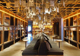 Центральная зона с диванами и полками, висящими листами и проходом к капсулам — уютная атмосфера книжной гостиной.