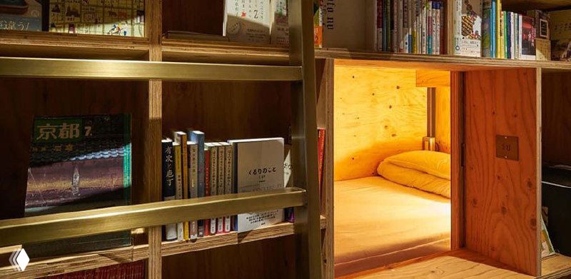 Капсула-кровать внутри деревянной ниши: матрас, подушки и занавеска — типичный спальный модуль Book and Bed в Токио.