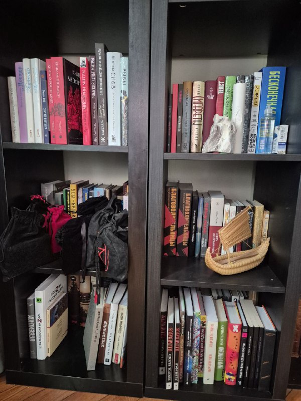 Полки с тканевыми сумками, мелкими корзинами и стопками книг; виден бытовой и личный характер коллекции автора.