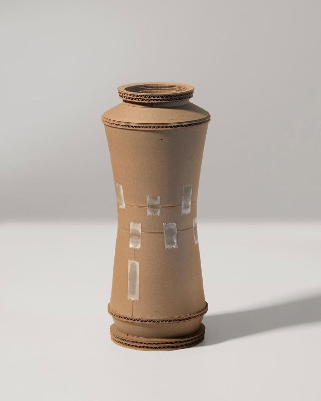 Высокая цилиндрическая форма-вазa автора, нейтральный свет, отчетливо видны швы, патинирование и небольшие вставки скотча или ремонта.