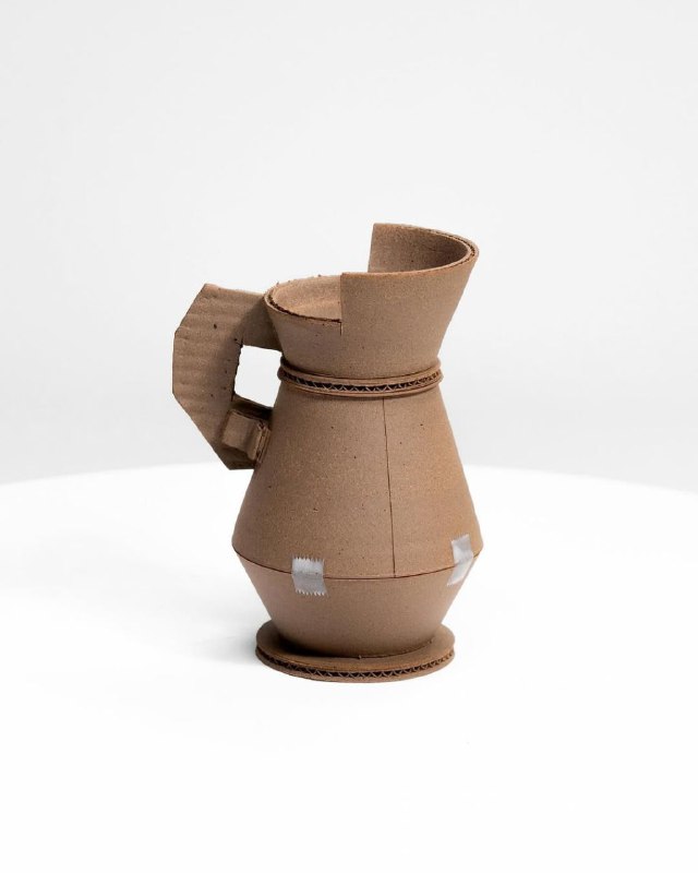 Короткая кувшиноподобная форма с широким горлышком и угловатой ручкой, простая пластика и текстура материала в студийной съемке.