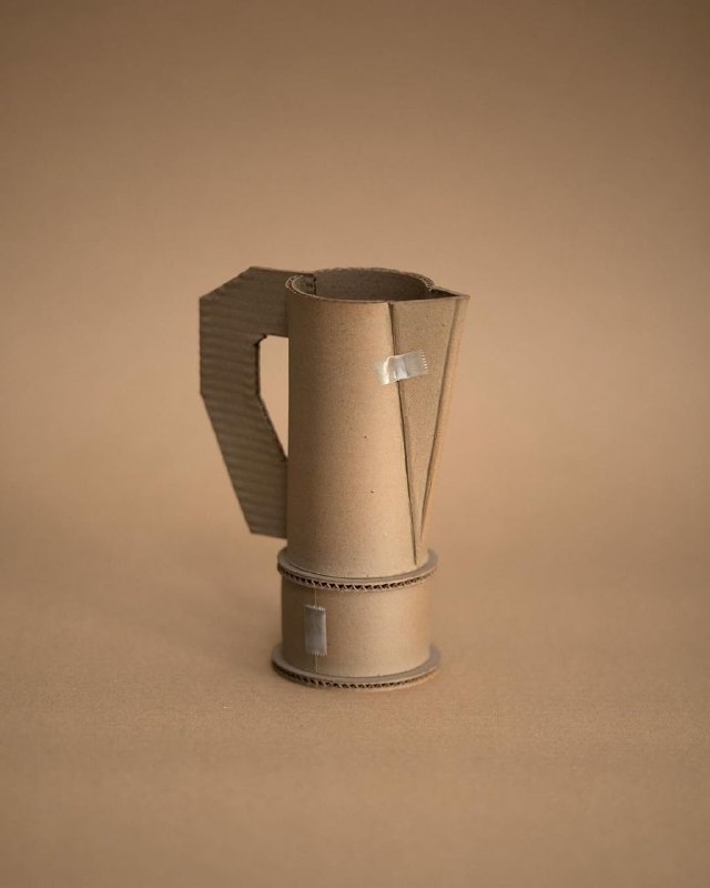 Фотография высоко стоящей графиноподобной формы с выраженной ручкой и заметными стыками материала, тёплый бежевый фон.