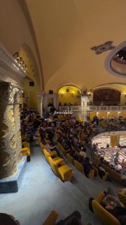 Ряд кресел и балконный уровень в Giunti Odeon: посетители рассаживаются, видно сочетание кинотеатра и книжного пространства в одном фойе.