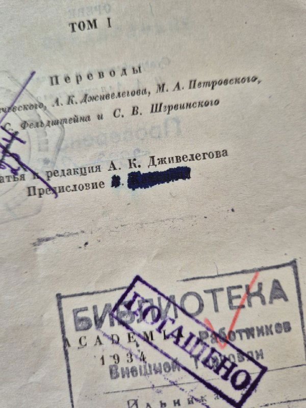 Крупный план разворота: вымараное имя в предисловии, печати 'Библиотека' и перечёркивания синей ручкой на фоне бумаги.