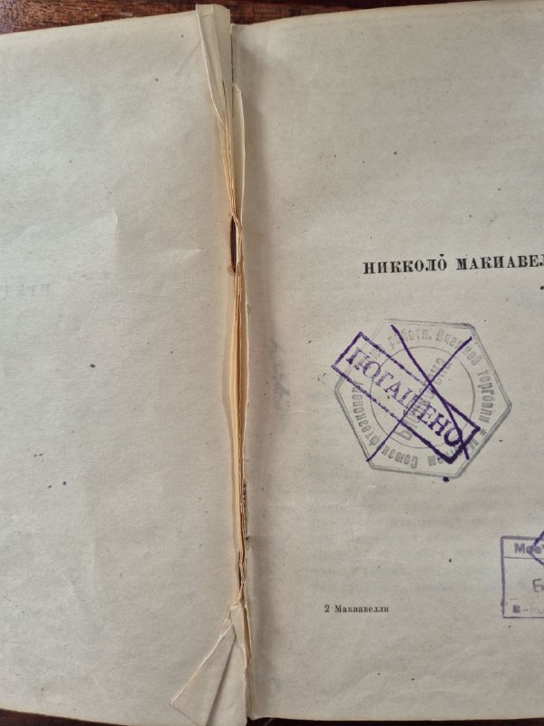 Снимок корешка и внутреннего сгиба книги: видны расслоение блока, следы вырезанных страниц и общая хрупкость бумаги.