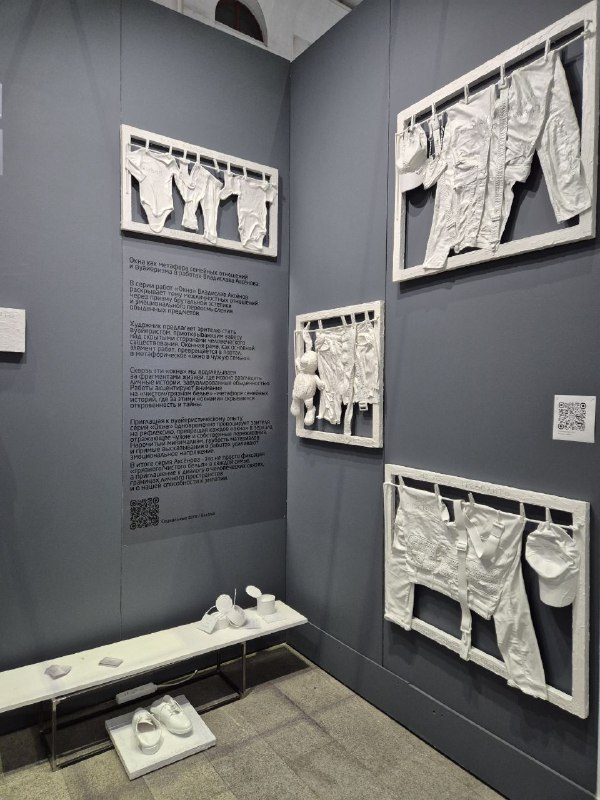 Инсталляция из гипсовых слепков одежды и белья, все элементы белые и подвешены на серой стене — композиция из бытовых форм.