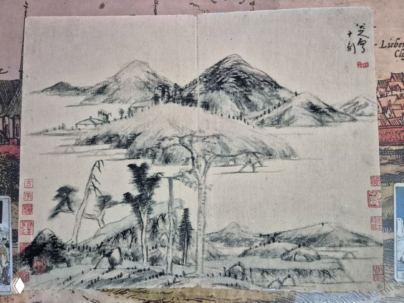 Разворот с более спокойным пейзажем: невысокие холмы, деревья и сакральная композиция «гора‑вода», выполненная в традиционной технике.