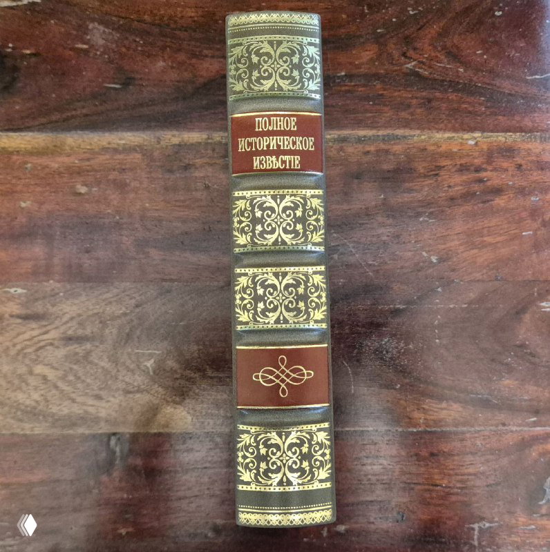 Крупный план корешка книги с тиснёным золотым орнаментом и надписью «Полное исторические известие» — вид оформления переплёта.
