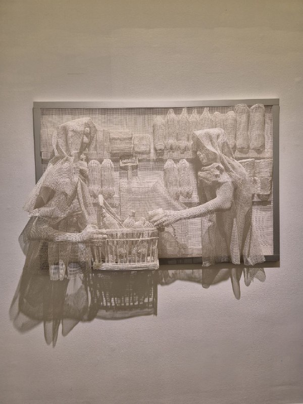 Барельефная рельефная композиция в монохроме, висящая на стене, с детализированными фигурами и тенями на поверхности.