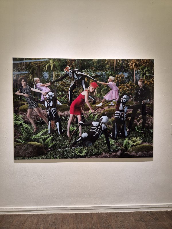 Картина с фигурами в сценическом антураже: костюмы и сценография, насыщенные цвета и контрастные элементы на полотне.