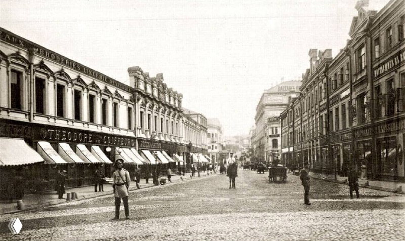 Чёрно-белая архивная фотография Кузнецкого Моста с прохожими, вывесками и старинной застройкой конца XIX — начала XX века в Москве.