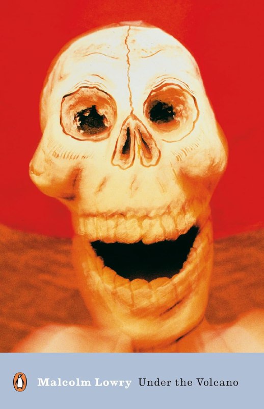 Обложка «Под вулканом» Малкольма Лоури: стилизованный череп на тёплом красновато-жёлтом фоне, выразительная иллюстрация и контрастные цвета.