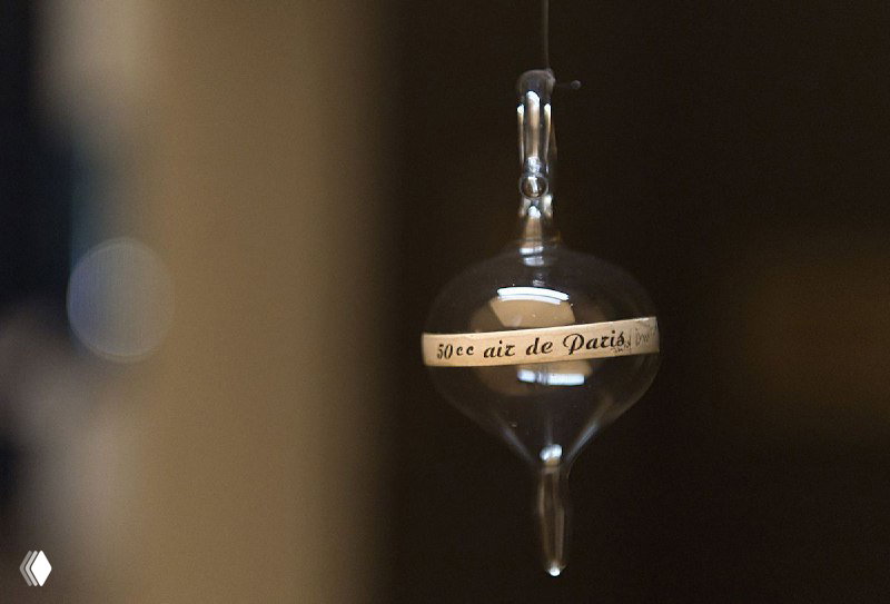 Макросъёмка стеклянного шарика с надписью «une air de Paris», размытие фона и игра света, тонкая атмосферная деталь.