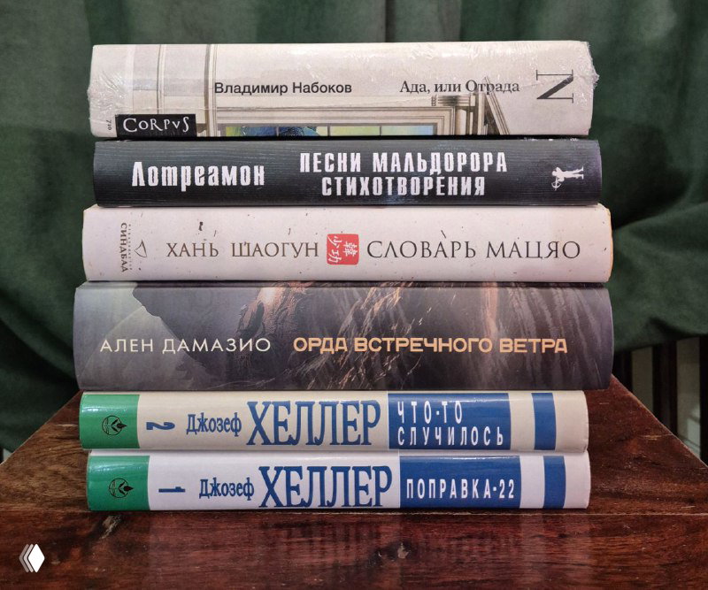 Фотография стопки книг с бумажными и твердыми переплетами на зелёном фоне; видны корешки и части обложек разных изданий.