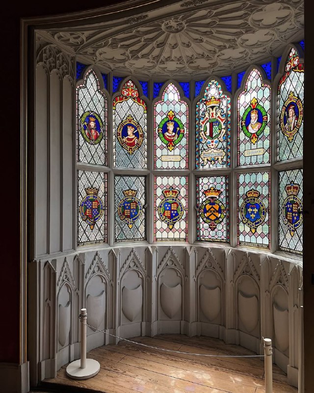 Полукруглое окно-апсида с витражами и гербами в библиотеке Strawberry Hill House: цветное стекло в деревянной раме и декоративная панель под ним.