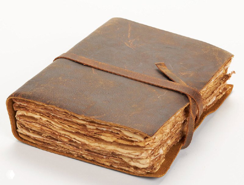 Старый потрёпанный том в кожаном переплёте с нитями и потёртыми страницами; экспонат, имитирующий древнюю потерянную книгу для выставки.