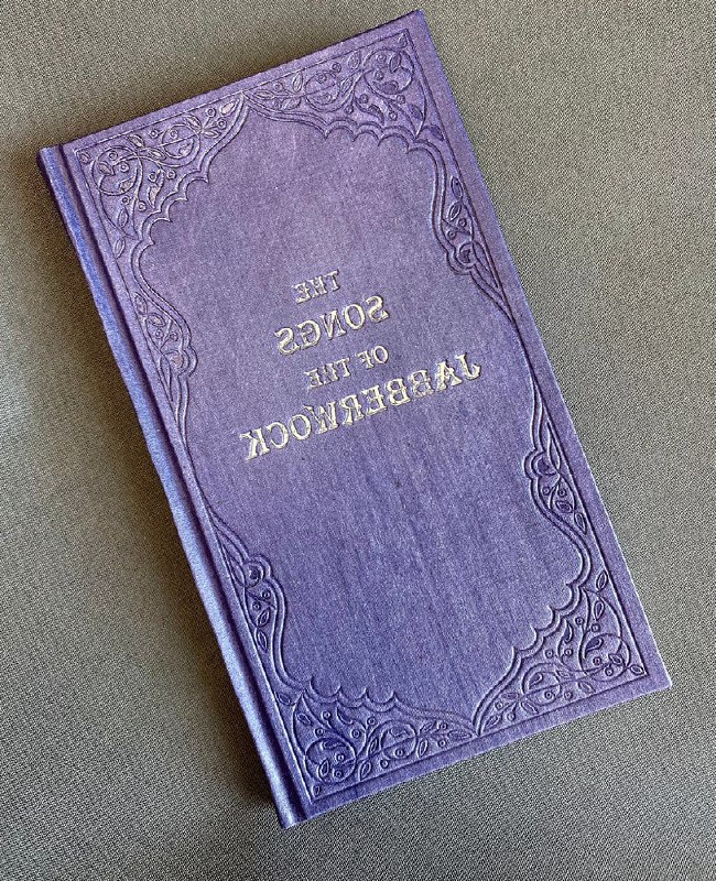 Фиолетовая изящная книга в декоративном переплёте с золотым тиснением, как иллюстрация к упоминаемой в тексте «Песням Бармаглота».